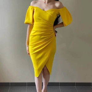 Gul offshoulder klänning med puffärm - Snygg gul klänning med off-shoulder och puffiga, korta ärmar. Omlottdetalj framtill och drapering i midjan skapar en riktigt trendig siluett. Perfekt för dig som vill sticka ut med både färg och stil. Klänningen har kort längd och markerad midja. Köpt från ASOS och endast använd en gång.