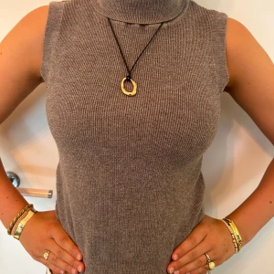 Ärmlös ribbad polotopp  - Säljer en grå-beige ärmlös polotopp i ribbstickad design. Toppen är figurnära och materialet är mjukt och stretchigt. Perfekt nu när sensommaren och hösten närmar sig. Passar både xs och s. Helt oanvänd och säljer för att jag redan tagit bort lappen. Priset är diskuterbart 