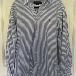 Ralph lauren skjorta - Säljer nu min skitfeta Ralph lauren skjorta i randig blå/vit färg! | Passar bra till både sommarfesterna och vardagsakgiviteterna. | Storlek S. | Fint skick förutom tre hål (5 bilden) som är lagade! | Släng iväg en signal vid funderingar så svarar jag snabbt. |