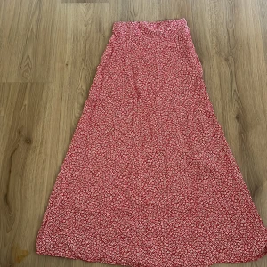 Röd långkjol med blommigt mönster - Superfin röd långkjol med vitt blommigt mönster och diskret dragkedja i sidan. Älskar verkligen den här kjolen och passar så bra med en röd eller vit tröja till❤️