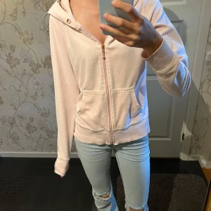 Ljusrosa hoodie med dragkedja - Mysig ljusrosa hoodie med huva och dragkedja framtill. Jackan har två fickor på magen och ribbade muddar vid ärmslut och nederkant. Perfekt för chill dagar eller när du vill ha en enkel och snygg look.