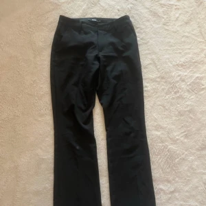 Svarta kostymbyxor från BikBok - Klassiska svarta lågmidjade kostymbyxor från BikBok i rak modell. Använt 1 gång för dom är förstora på mig, finns en nagellim fläck under knäet på byxorna men inget som syns på långt håll.