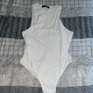 Vit ärmlös body.  - Säljer en stilren vit bodysuit med högt skurna sidor och ärmlös design. Perfekt att styla med jeans eller kjol för en clean look. Mjuk och stretchig i materialet för en bekväm passform. Storlek M men passar mig som är en S 