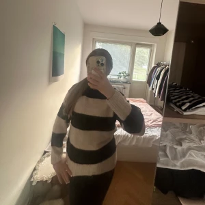 Randig stickad tröja i svart och beige - Säljer en oversized stickad tröja med breda svarta och beige ränder. Tröjan har lång ärm, rund hals och är riktigt mjuk och skön. Perfekt för kyliga dagar när du vill vara både bekväm och snygg. 150 men passar xxs🩷
