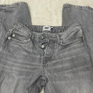 Grå raka jeans från 157 - Snygga grå jeans från 157 med klassisk femficksdesign och raka ben. Jeansen har normal passform och är tillverkade i slitstarkt bomullstyg. Perfekta för dig som gillar en enkel och clean look med vintagekänsla.