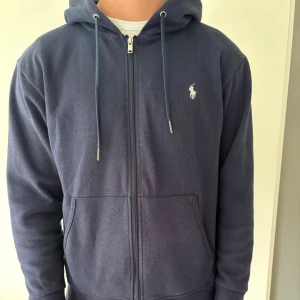 Mörkblå zip hoodie Polo Ralph Lauren - Säljer en snygg mörkblå hoodie med dragkedja, huva och snörning.
