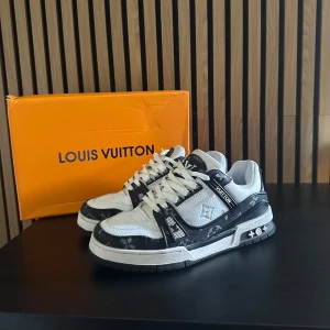 Louis Vuitton trainers - Exklusiva Louis Vuitton sneakers i svart och vitt med klassiskt LV-monogram. Skorna har snörning, rund tå och platt sula. Tillverkade i en mix av skinn och textil med tydliga logodetaljer på tunga och häl. Snygg kontrast mellan svart och vit, perfekt för dig som gillar statement sneakers. Hör av er vid eventuella funderingar! 🤩🤝🏼
