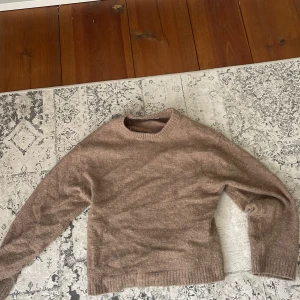 Beige stickad tröja från Gina Tricot - Mysig beige stickad tröja från Gina Tricot i ullblandning. Tröjan har rund halsringning, ribbade muddar och lång ärm. Perfekt för lager-på-lager och chill höst- eller vinterstil.