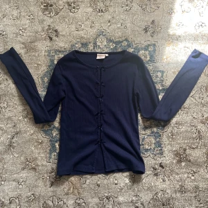 Mörkblå långärmad topp från Nelly - Mörkblå långärmad topp från Nelly i ribbat bomullsmaterial. Toppen har smickrande slim fit.