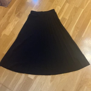 Svart långkjol från Kappahl XS - Säljer en svart långkjol från Kappahl i storlek XS. Kjolen har ett snyggt plisserat fall och är helt enfärgad, vilket gör den enkel att matcha. Perfekt för dig som gillar stilrena och klassiska plagg med lite extra flow.