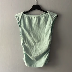 Ljusgrön/ljusblå ribbad topp från Cider i storleken xs💕 - Säljer en ljusgrön /ljusblåt ribbad topp från Cider i storlek XS. Toppen är ärmlös med breda axelpartier och har en lätt rynkad detalj i sidorna för en snygg passform. Perfekt för dig som gillar stilrena och fräscha plagg med en twist.
