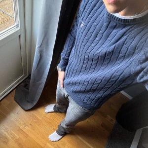 Marinblå kabelstickad tröja GANT M - Säljer en marinblå kabelstickad tröja från GANT i storlek M. Tröjan har rund hals, ribbade muddar och GANT-logga broderad på bröstet. Perfekt för dig som gillar klassisk och stilren look. Materialet är mjukt och skönt, passar till jeans eller chinos.