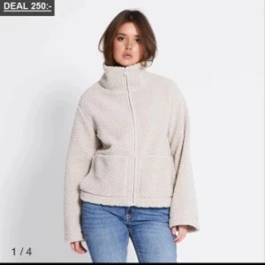 Beige teddyjacka med dragkedja - Mysig beige teddyjacka med hög krage och dragkedja framtill. Jackan har två stora fickor och en avslappnad passform som ger en chill vibe. Perfekt för kyliga dagar när du vill vara både varm och snygg.