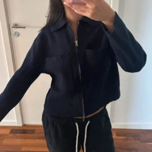 Mörkblå overshirt med dragkedja - Snygg mörkblå overshirt med dragkedja framtill och två stora bröstfickor. Jackan har en klassisk krage och raka, långa ärmar. Perfekt för lager-på-lager och enkel att styla till olika outfits.