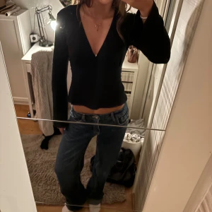 Svart omlottopp  - Svart långärmad omlottopp med djup v-ringning och lätt utsvängda ärmar. Sitter figurnära över midjan och har en snygg, enkel look. Tröjan är från ginatricot och har Max använt den 4 ggr