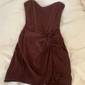 Brun axelbandslös klänning - Snygg brun axelbandslös klänning med draperad detalj framtill. 