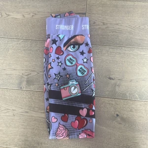 Färgglada leggings från Stronger - Säljer ett par färgglada leggings från Stronger med ett coolt pop art-mönster i lila, rosa och rött. De är tillverkade av återvunnen polyester och elastan för en bekväm passform. Perfekta för träning eller en färgglad vardag! Används inte längre pga dom blivit försmå , väldigt bra skick ✌🏻🤝🏻