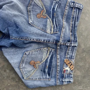  lågmidjade jeans - Snygga blå jeansshorts från Grase Jeans med broderade detaljer på bakfickorna. Perfekta för en avslappnad stil med en touch av unik design. Klassisk femficksmodell med knapp och dragkedja framtill. De är pytte insydda på benen för att göra de mer lågmidjade men tror de är lätt att sprätta upp om de ej önskas