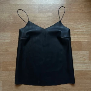 Svart läder linne med tunna axelband - Snyggt svart läder linne med tunna axelband och v-ringning.