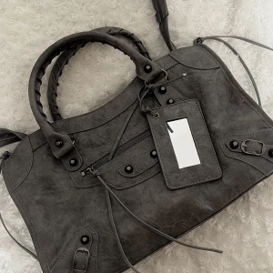 City bag - Èlise - (OBS! inte begagnad! Finns även att beställa via vår hemsida www.ivysthlm.se) CITY BAG – Den perfekta statment väskan som livar upp varje vardags-outfit. Lika praktisk som snygg och fungerar både till skola & fest – Ja, din dator får plats! (väskan levereras med ett långt, justerbart axelband för extra bekvämlighet) Storlek: 38×10×23 cm Finns även tillgänglig i svart och röd! Äkta läder