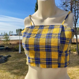 Croppad topp med justerbara band - Gul- och blårutig croptop med justerbara axelband. Bra skick, använd ett fåtal gånger. På lappen står det “Sizaful”, inget märke jag känner till men toppen är superfin och känns stabil i kvaliteten.
