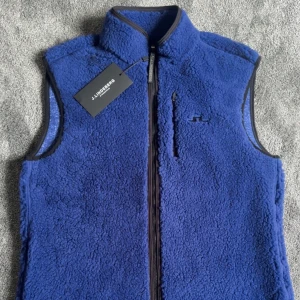 Blå fleeceväst från J.Lindeberg - Fet blå fleeceväst från J.Lindeberg med dragkedja framtill. Helt oanvänd och lappen är kvar som på bilden.                                                Storlek S passar även M                               