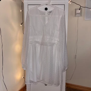 Vit klänning från Bubbleroom - Säljer en elegant vit klänning från Bubbleroom med v-ringning och långa ärmar. Klänningen har ett subtilt prickigt mönster och en dragkedja i ryggen. Perfekt för studenten ! ✨