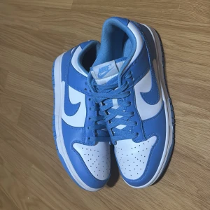 Nike Dunk i blått och vitt - Snygga Nike Dunk sneakers i en fräsch blå och vit färgkombination. Skorna har klassisk snörning och en bekväm passform. Perfekta för en stilren look. (Hör av er vid minsta fundering)🤝🙌