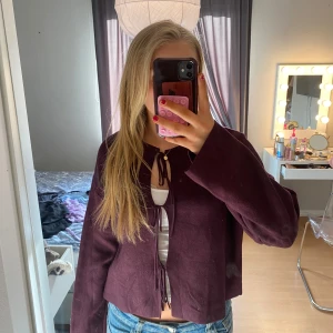 Vinröd tröja från Gina Tricot - Säljer en vinröd tröja från Gina Tricot med knytning framtill. Tröjan har långa ärmar och en ribbad kant vid halsen. Strl M