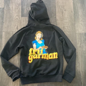 Revenite Hoodie - Snygg svart hoodie med en stor färgglad tryck på baksidan föreställande en kvinna och texten 'fru gårman'. Hoodien är från Revenite, och var deras sista släpp innan dom slutade. Oanvänd. 