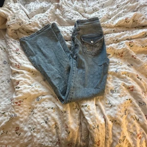 Blå jeans med broderad ficka - Snygga blå jeans med en unik broderad detalj på bakfickan. Perfekta för dig som vill ha något extra i garderoben. Klassisk passform och stilren design. lowwaist. en knapp har trillat av på baksidan men har den kvar och den är nog enkel o så fast igen