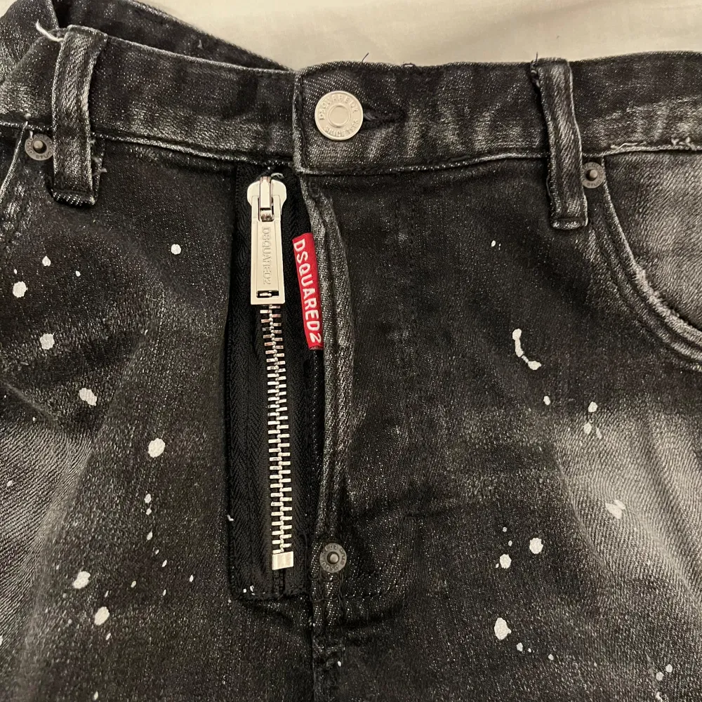 Snygga svarta jeans från Dsquared2 med unikt stänkmönster. Byxorna har en dragkedja och knapp framtill samt en cool detalj med Dsquared2-logga vid fickan. Perfekta för dig som vill sticka ut med en edgy stil. Pris sänks vid snabbaffär.. Farkut & Housut.