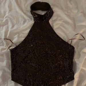 Brun glittrig halterneck topp från Gina Tricot - Säljer en snygg brun halterneck topp från Gina Tricot. Toppen är glittrig och perfekt för festliga tillfällen. Storlek M, hör av dig vid intresse!🩷Aldrig använd!
