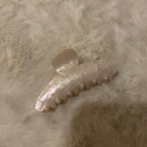 Pärlemorskimrande hårklämma - Snygg hårklämma i pärlemorskimrande material. Perfekt för att snabbt och enkelt sätta upp håret med stil. Klämman har en elegant och tidlös design som passar till många olika tillfällen.