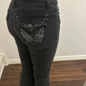 Svarta jeans med paljettdetaljer - Jättefina svarta lågmidjade jeans med utsvängda ben och paljettdetaljer på fickorna, bara använda 1 gång, storlek 32 regular, jag är 164cm☺️💗