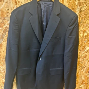 Svart kavaj från Cavaliere - Elegant svart kavaj från Cavaliere med klassisk design. Kavajen har en enkelknäppning och är tillverkad i ett stilrent material. Perfekt för formella tillfällen.