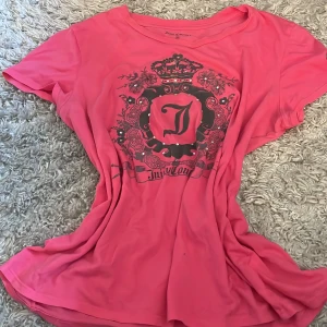 Rosa t-shirt från Juicy Couture - Säljer en snygg rosa t-shirt från Juicy Couture med ett stort tryck framtill. T-shirten har korta ärmar och en rund halsringning. Perfekt för en avslappnad stil. Hör av dig vid intresse! 💖