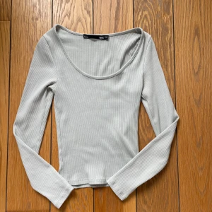 Grå/grön ribbad långärmad topp  - En figurnära topp som är u-ringad.