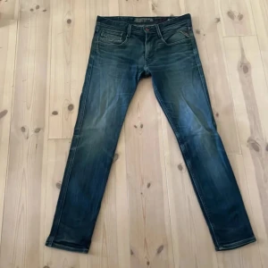 Replay Anbass jeans blå - Snygga blå Replay Anbass jeans med slim fit och klassisk femficksdesign. Jeansen har en lätt tvättad look med slitningar och är tillverkade i mjukt denim. Perfekta för dig som gillar en modern och smal siluett.