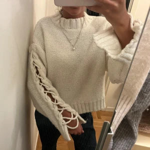 Vit stickad tröja med snörning - Säljeer denna så snygga och coola vita stickad e tröjan med unika snörningsdetaljer längs ärmarna💞