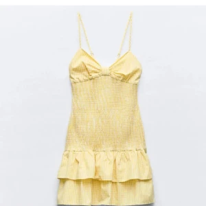 Gul kort sommarklänning med volang - Söt gul kortklänning med tunna axelband, volang nertill och diskret randigt mönster. Helt ny, har aldrig använt 