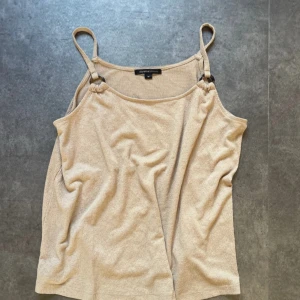 Beige linnetopp från Mywear Woman - Säljer en beige linne/ topp från Mywear Woman i storlek M men passar även mig som brukar ha xs/s🫶🏼. Toppen har smala axelband med snygga ringdetaljer i plast och är tillverkad i ett mjukt, frottéliknande material. Perfekt för varma dagar och enkel att matcha med jeans eller kjol.
