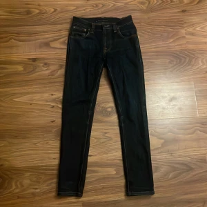 Nudie Jeans Grim Tim Dry Navy 28/32 - Säljer ett par mörkblå Nudie Jeans Grim Tim då de är för små för mig. Passformen är slim och benen är raka med en modern look. Sitter väldigt litet i storleken. Skulle säga att de passar någon runt 160-165cm och runt 40-45kg. Hör av dig vid funderingar!😁