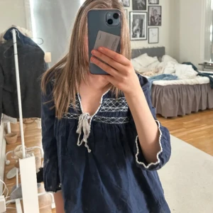 Mörkblå blus - Säljer en mörkblå blus från odd Molly med vita broderade detaljer upptill och knytband vid halsen. Perfekt för sommaren 