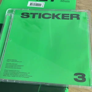Sticker (The 3rd Album) - Sticker är NCT 127:s tredje album, perfekt för dig som älskar K-pop! Albumet har en snygg grön design, coola fotokort och bilder på medlemmarna. En samlarfavorit för fans som vill ha något unikt i sin hylla. Den är köpt från Bengan i Stockholm, 