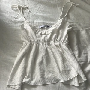 Vit linnetopp med volang - Supersöt vit linnetopp från 157 med smockad struktur, volangkant vid ringningen och tunna axelband som knyts. Använd 1 gång. Pris går att diskutera🤍