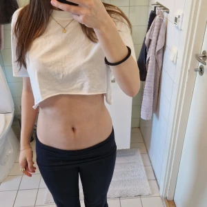 Vit croppad t-shirt i bomull - Enkel och stilren vit croppad t-shirt med rund hals och korta ärmar. T-shirten är loose fit och gjord i mjuk bomull, perfekt för en avslappnad look. Passar dig som gillar minimalistisk stil och vill ha en basic topp i garderoben.