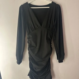 Svart klänning  - Svart klänning med långa ärmar och v-ringning. Klänningen har rynkdetaljer på sidorna och sitter tajt. Knappt änvönd, fint skick. Från shein. Storlek M
