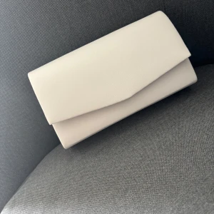 Vit kuvertväska - Stilren vit kuvertväska med enkel design och magnetlås. Väskan har en slät yta och ett rymligt fack på insidan. Perfekt för att bära det viktigaste när du vill hålla det minimalistiskt och cleant. Helt oanvänd✨