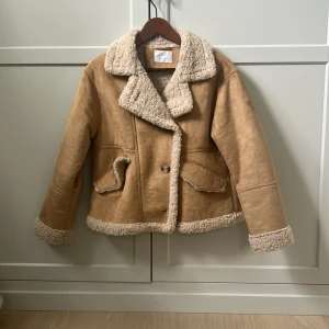 Beige teddyjacka från Zara, stl 164/XXS-XS - Säljer en beige teddyjacka från Zara i storlek 164. Jackan har mysigt teddyfoder på krage, ärmslut och nederkant samt två fickor framtill. Perfekt för kalla dagar och har en snygg, boxig passform med stora slag. Är 164 men passar som XXS-XS. !Använd fåtal gånger!